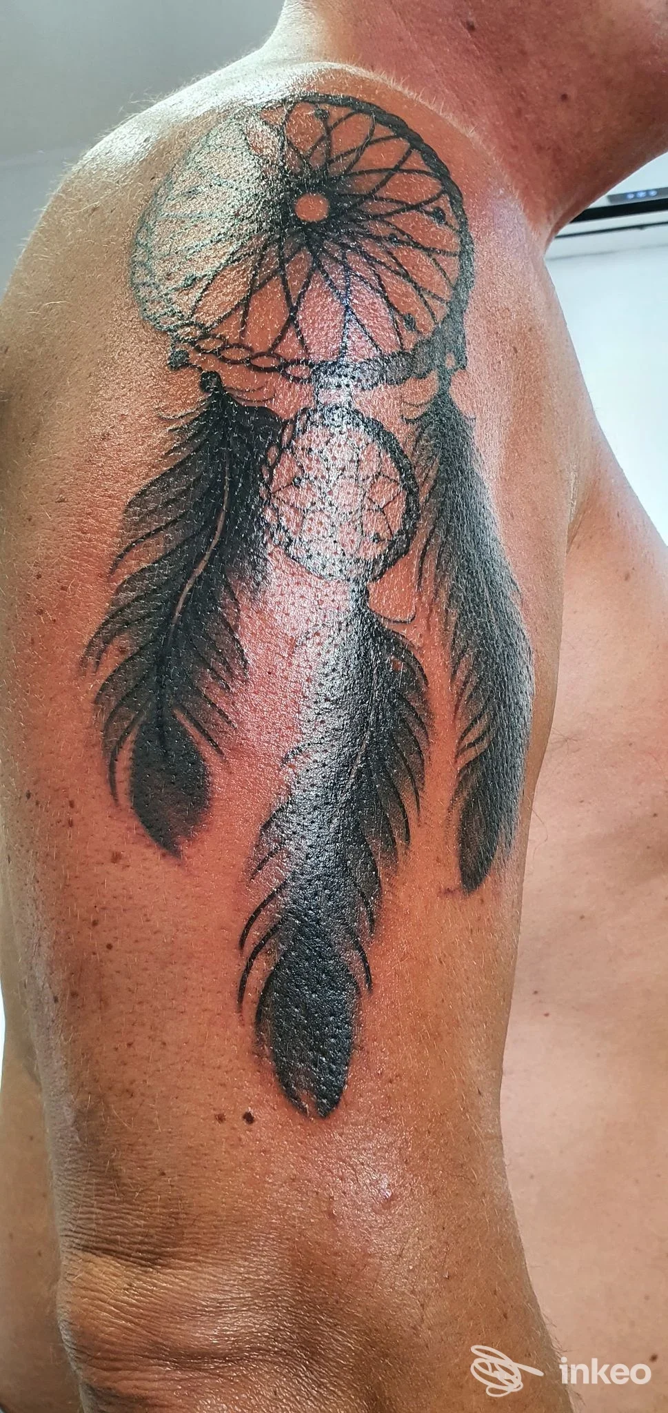 Grande tatuaggio dreamcatcher con tre piume su spalla e braccio, scatto del b/g tattoo a Livorno.