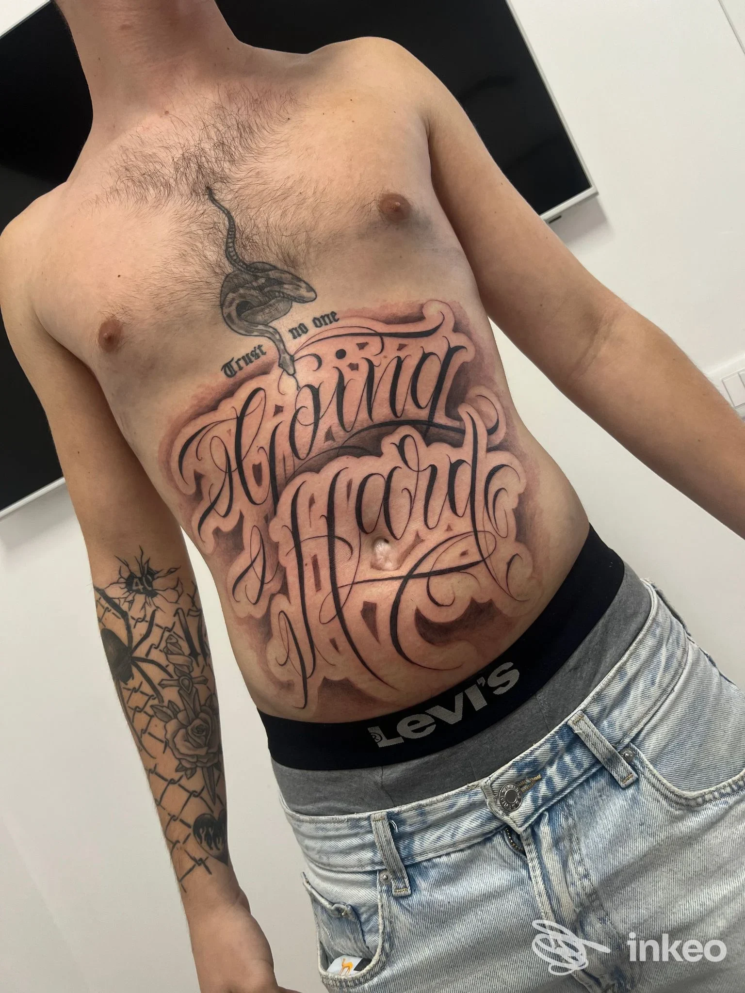 Ampio tatuaggio calligrafico nero sull'addome, foto fornita da 2L TATTOO & PIERCING STUDIO - Treviso.