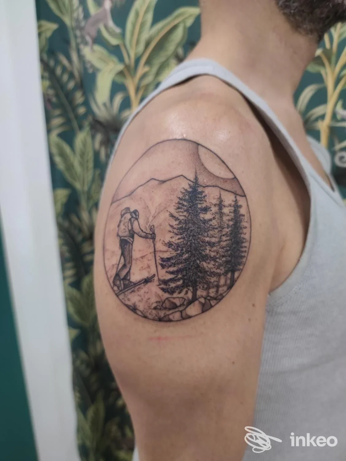 Tatuaggio circolare su spalla con paesaggio montano e camminatore, foto fornita da Darkwood, Bologna.