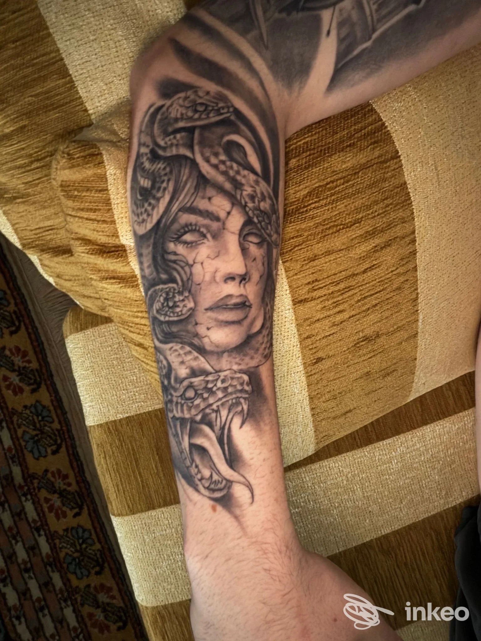 Tatuaggio in bianco e nero su avambraccio raffigurante volto femminile e serpenti — Dän Ink, Venezia.