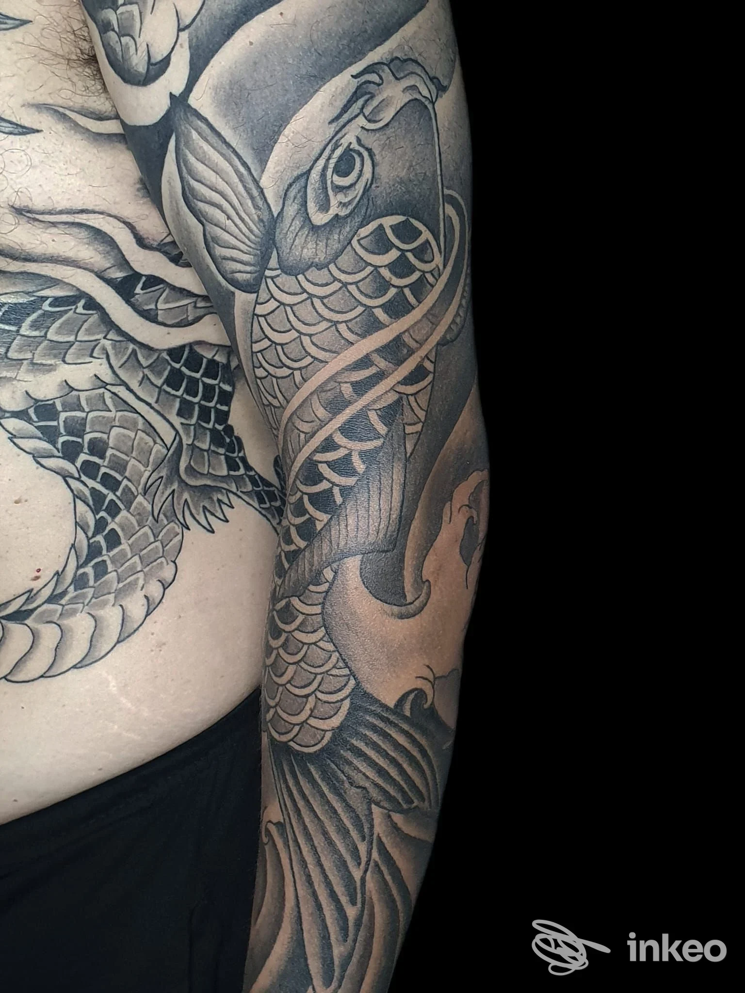 Tatuaggio a manica con carpa in nero e grigio, foto fornita da DARKO tattoo & piercing, Bologna.