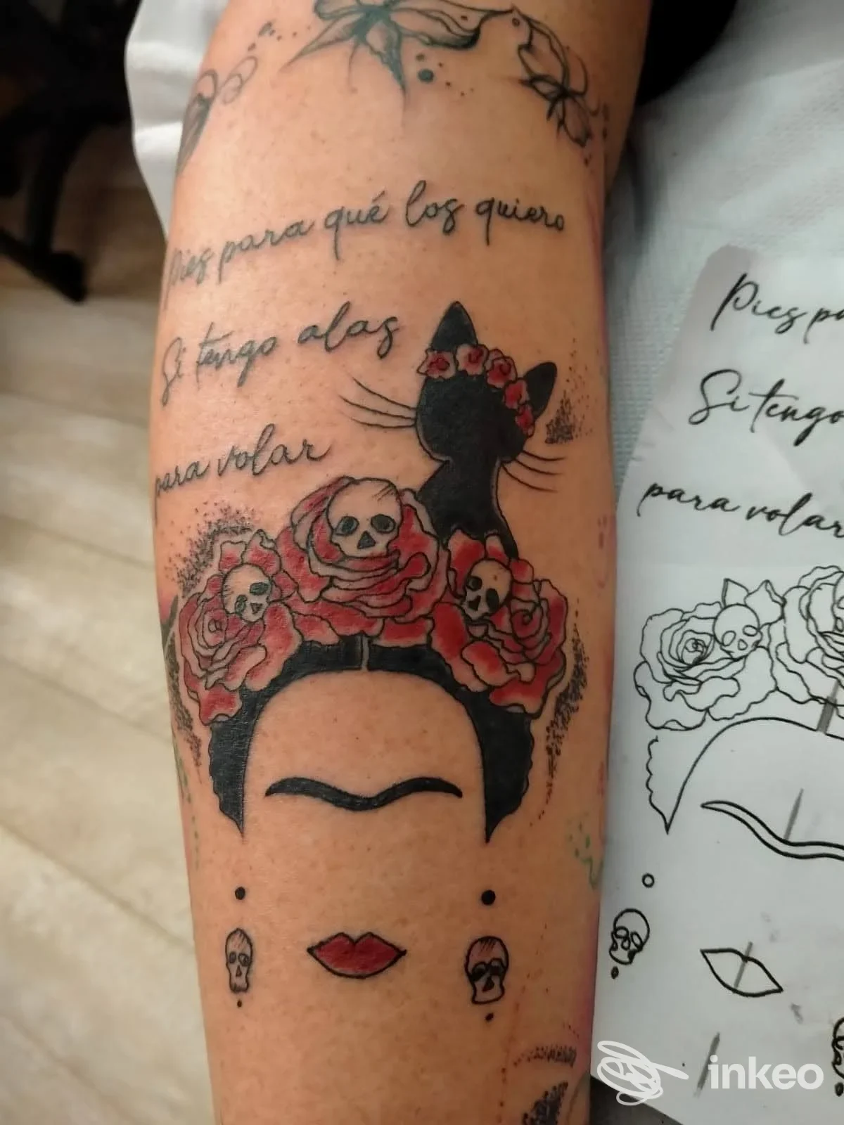 Tatuaggio su avambraccio con volto stilizzato, rose rosse e teschi — Antelia Tattoo, Piombino.