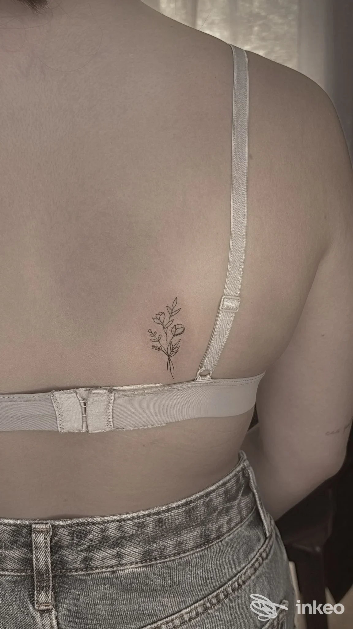 Piccolo tatuaggio botanico a linee sottili sul dorso, vicino allo spallaccio del reggiseno — Derm’Art Studio, Torino.