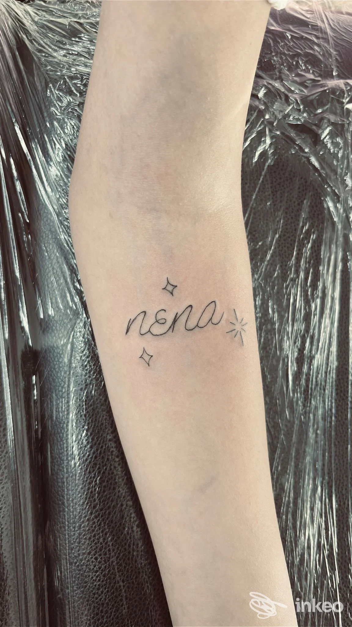 Tatuaggio minimal sul palmo interno dell'avambraccio con la scritta "nona" e piccoli stelline. Derm’Art Studio, Torino.