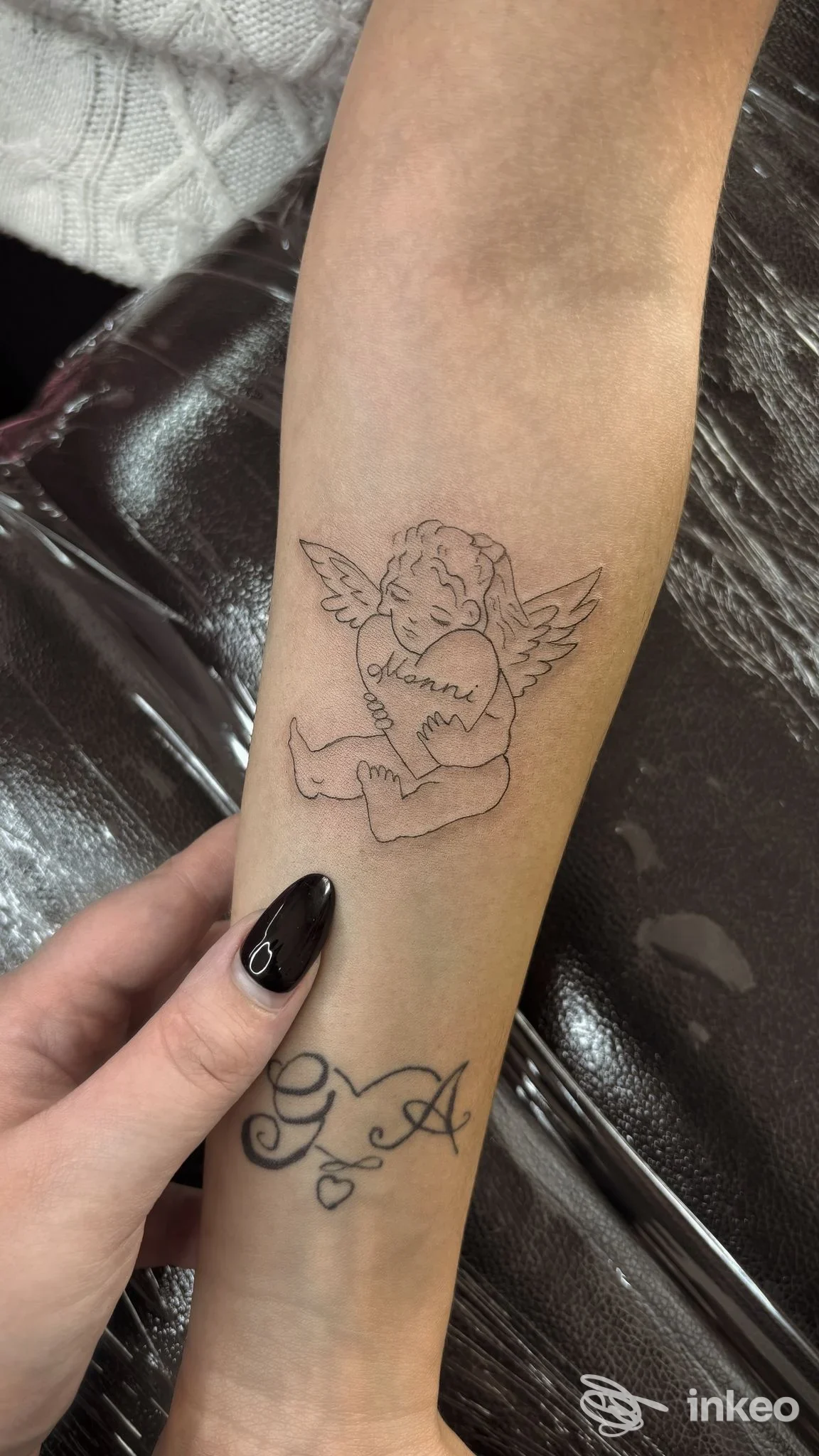 Tatuaggio linework di un angioletto con cuore sull'avambraccio, foto fornita da Derm’Art Studio, Torino.