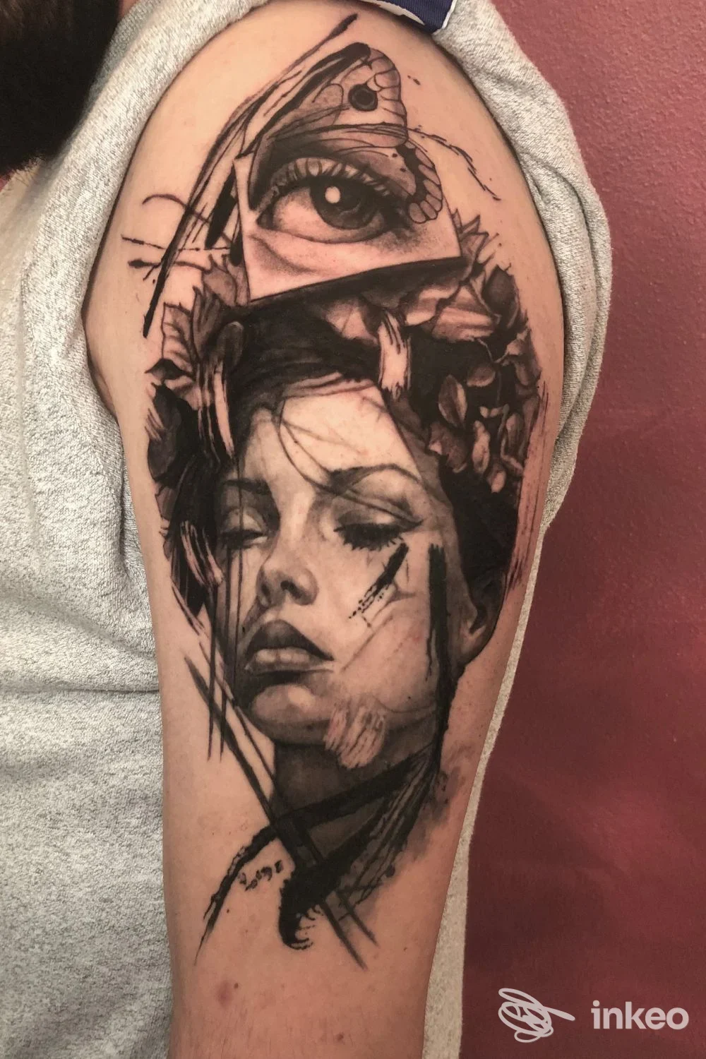 Tatuaggio realistico in nero su parte superiore del braccio, ritratto femminile e occhio sovrapposto — Nuovo Impero Tattoo Studio, San Cesario sul Panaro.