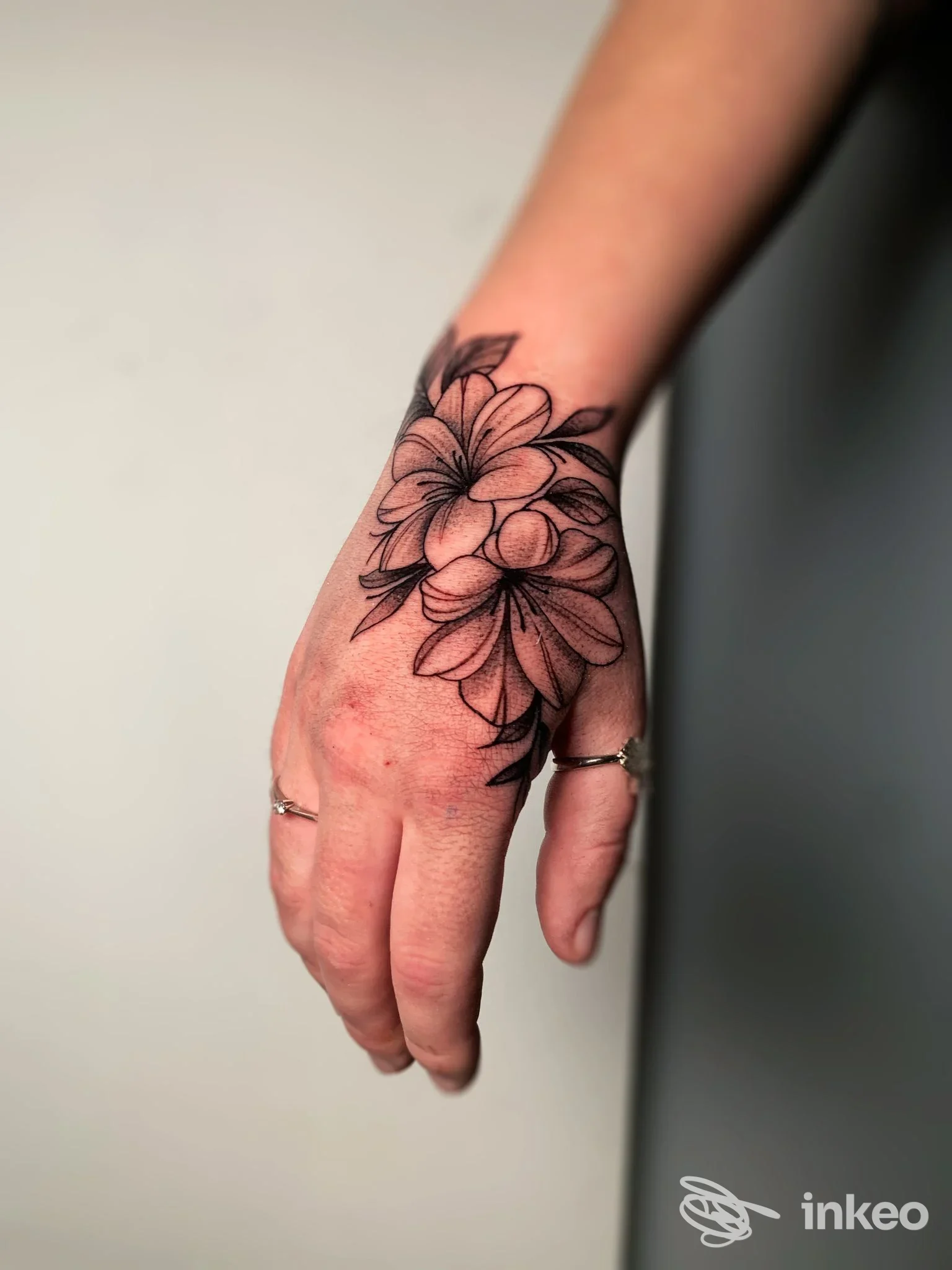 Primo piano di una mano con tatuaggio floreale nero sul dorso e polso, foto fornita da draive tattoo studio a Porto Viro.