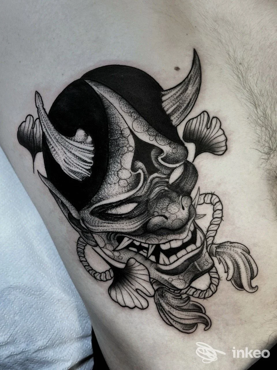 Tattoo raffigurante un demone con corna e decorazioni a corde, eseguito sulla pelle del braccio.