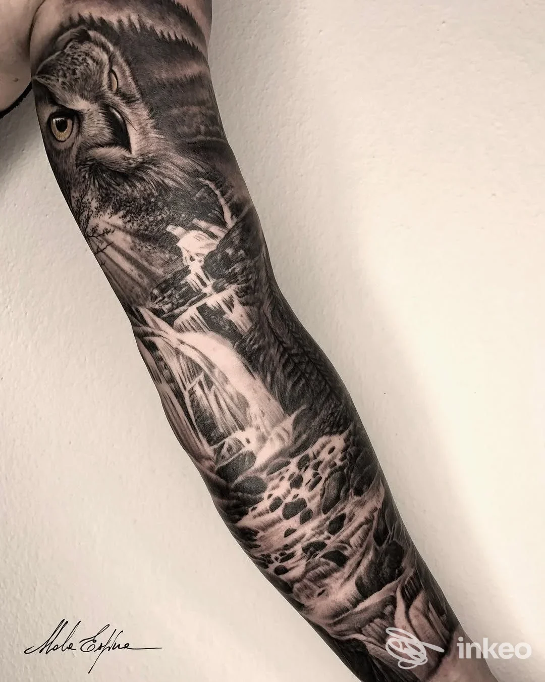 Tattoo realistico in bianco e nero su avambraccio, ritraente un animale fieristico e un paesaggio, lungo tutto l'avambraccio.