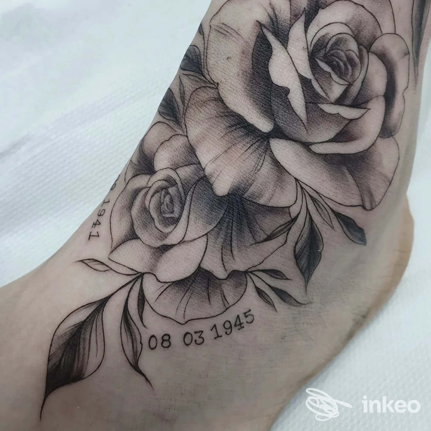 Tatuaggio realistico di rose e data sul lato del piede, foto fornita dallo studio Lady Purple Tattooer a Ravenna.