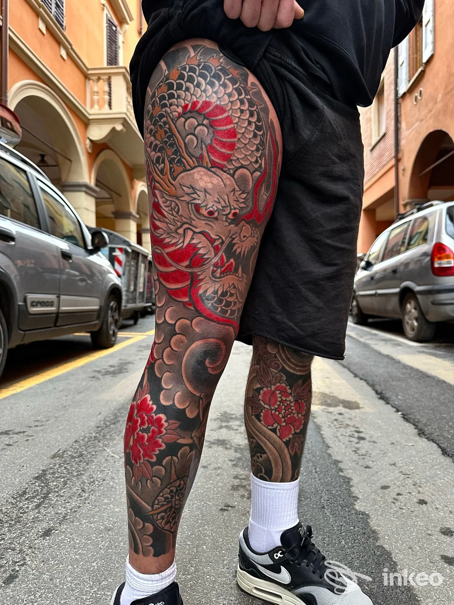 Ampio tatuaggio su coscia e polpaccio con drago e fiori, foto fornita da Sorry Mom Tattoo Bologna, dettaglio colore nero e rosso.