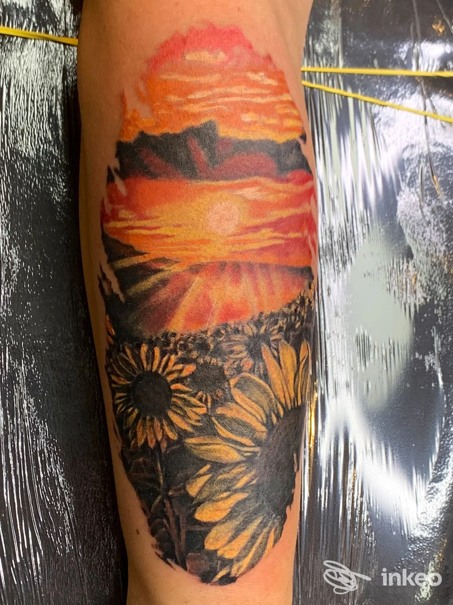 Tatuaggio colorato con tramonto e girasoli sull'avambraccio, foto fornita da The Max Tattoo a Lugo.