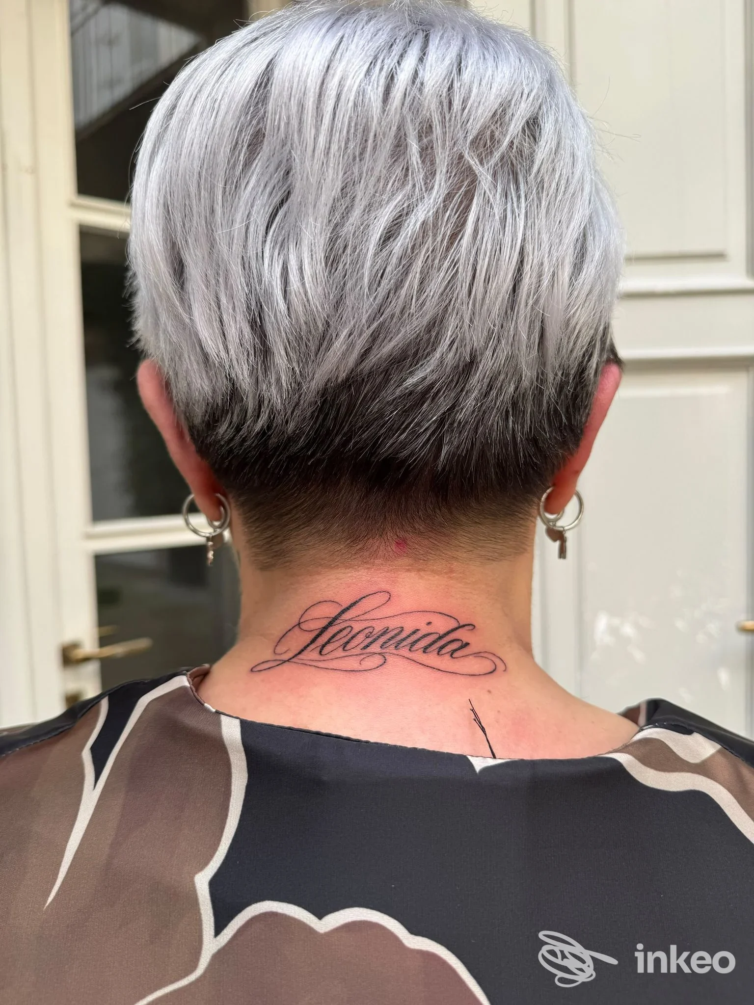 Tatuaggio in calligrafia con la scritta 'Leonida' sul retro del collo, fotografato per Happy Tattoo Club a Bra.