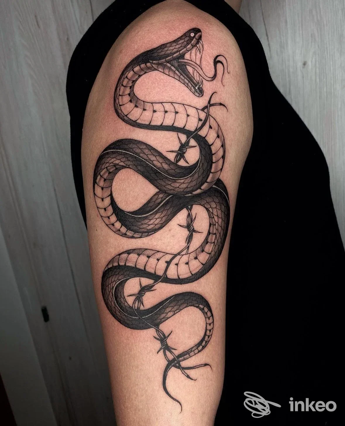 Tatuaggio a serpente nero sul braccio (bicipite) realizzato da Red Rose Tattoo, Scandicci.
