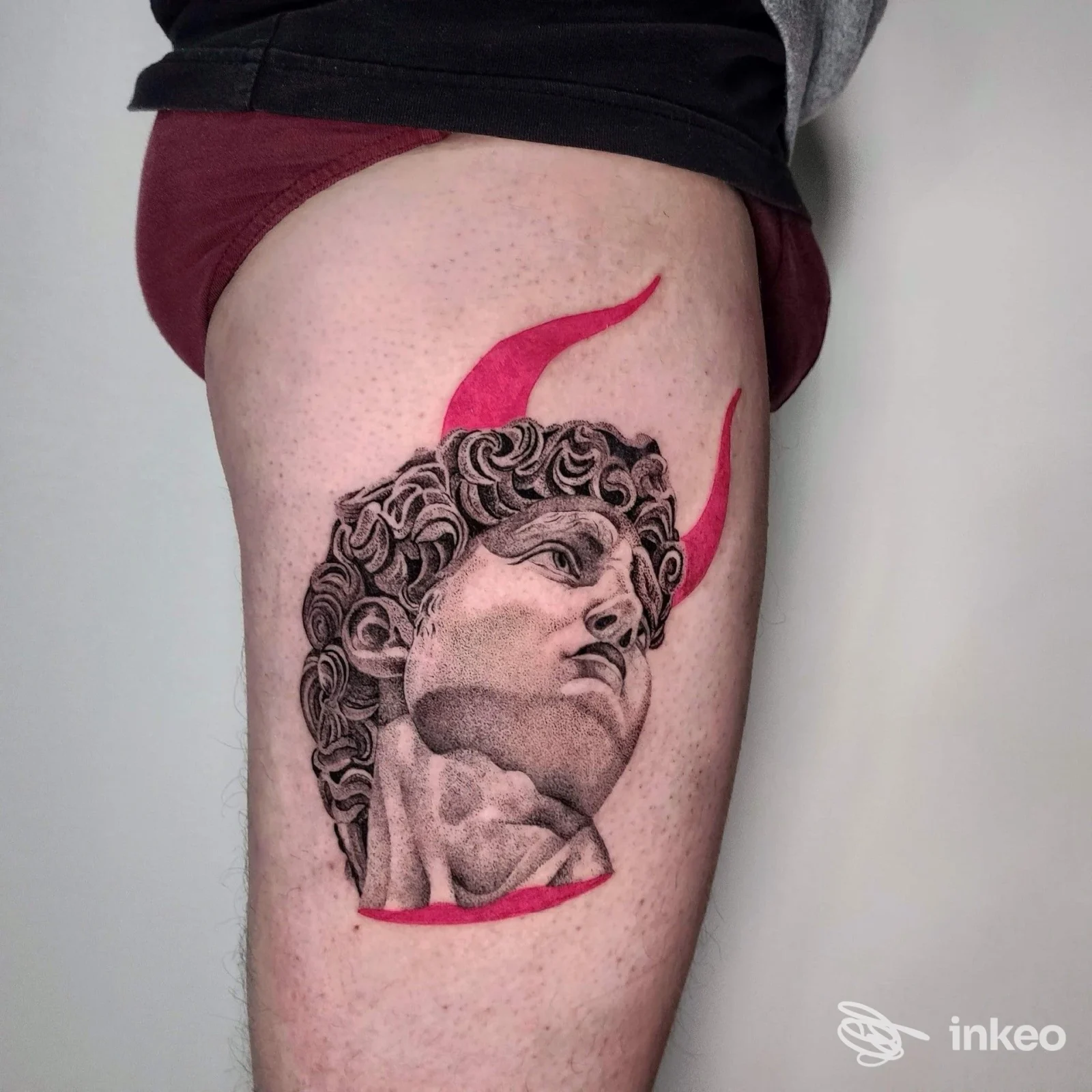 Tatuaggio su coscia di testa scultorea in bianco e nero con dettagli rossi, foto per Want Unconventional Lab & Tattoo, Bologna.