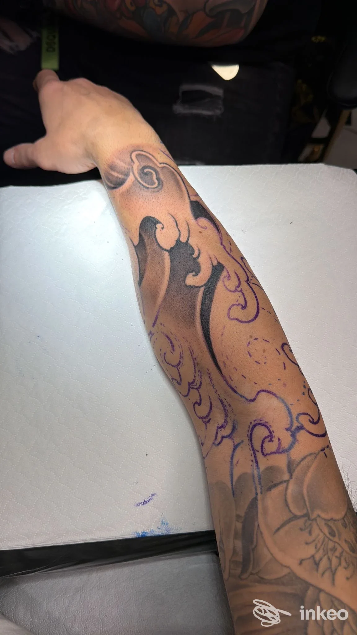 Avambraccio tatuato in primo piano, foto per Black Pyramid Tattoo a Zola Predosa con linee di guida viola e ombreggiature nere.