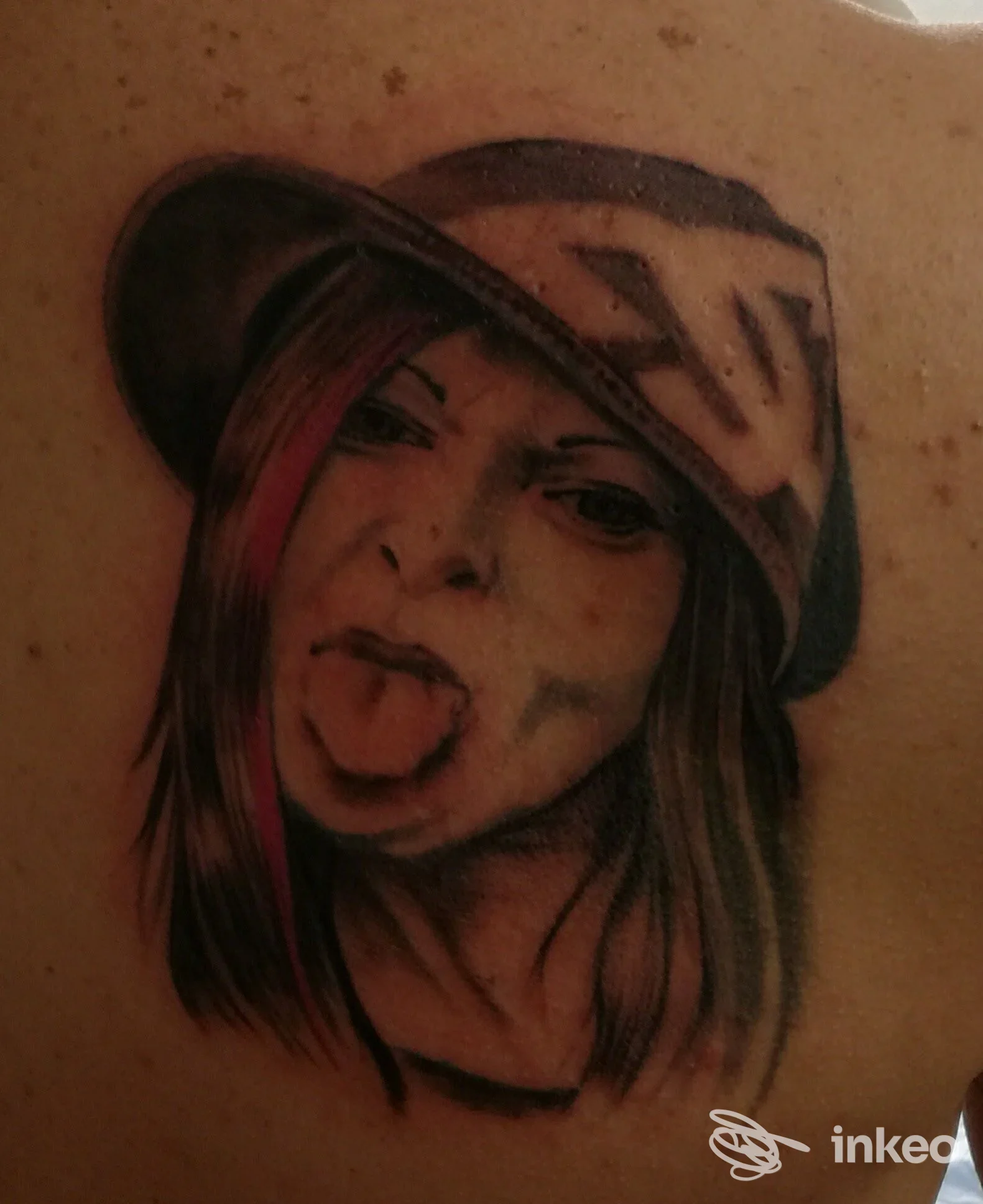 Tattoo realistico su pelle che raffigura una ragazza, con cappello, visibile sull’omero/avambraccio. Foto senza watermark o sovrimpressioni, stile realistico.