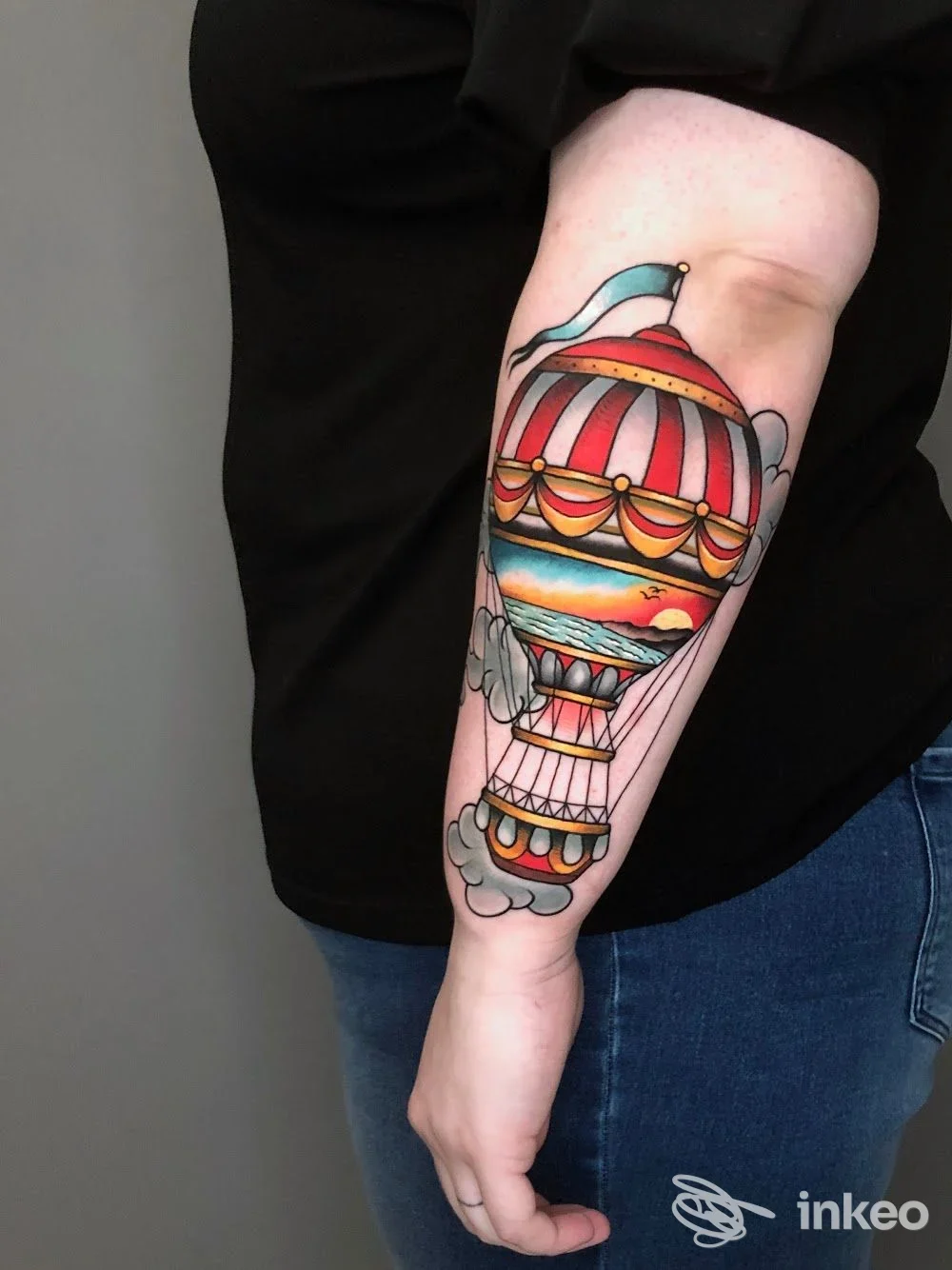 Tatuaggio su avambraccio di una mongolfiera colorata con cielo e nuvole, realizzato da Andrea Audisio Metamorfosi Tattoo Studio Cuneo, Cuneo.