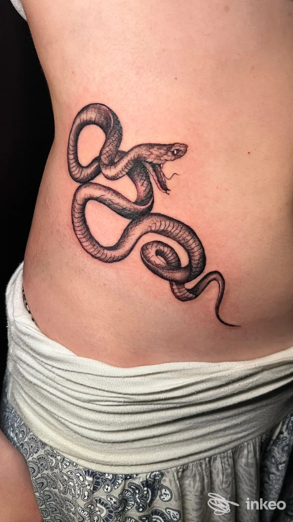 Tatuaggio a inchiostro nero di un serpente sul fianco, realizzato da Blood a Blood Tattoo Club, Bologna.
