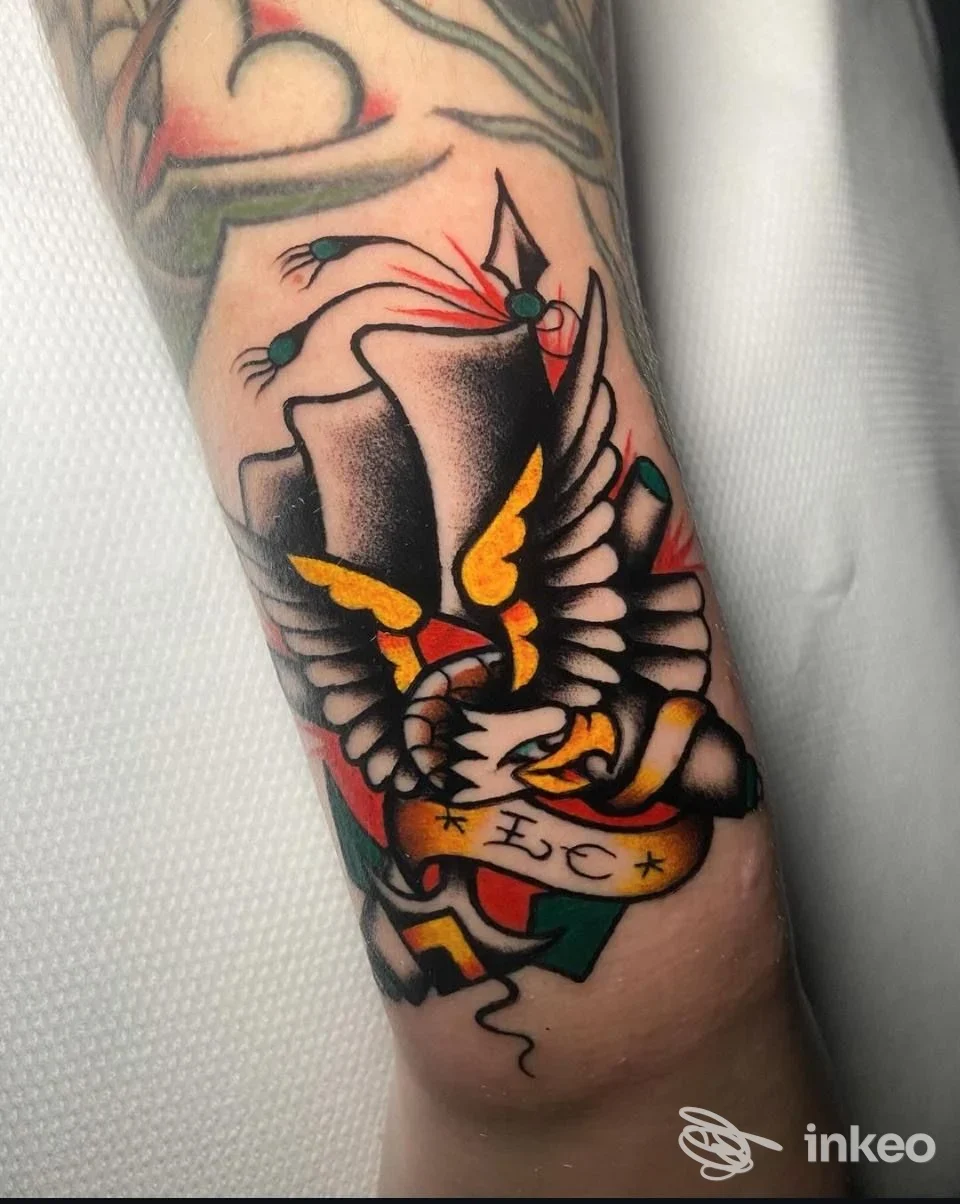 Tatuaggio tradizionale su avambraccio, uccello con cappello e stendardo — Black Panda Tattoo, Bologna.