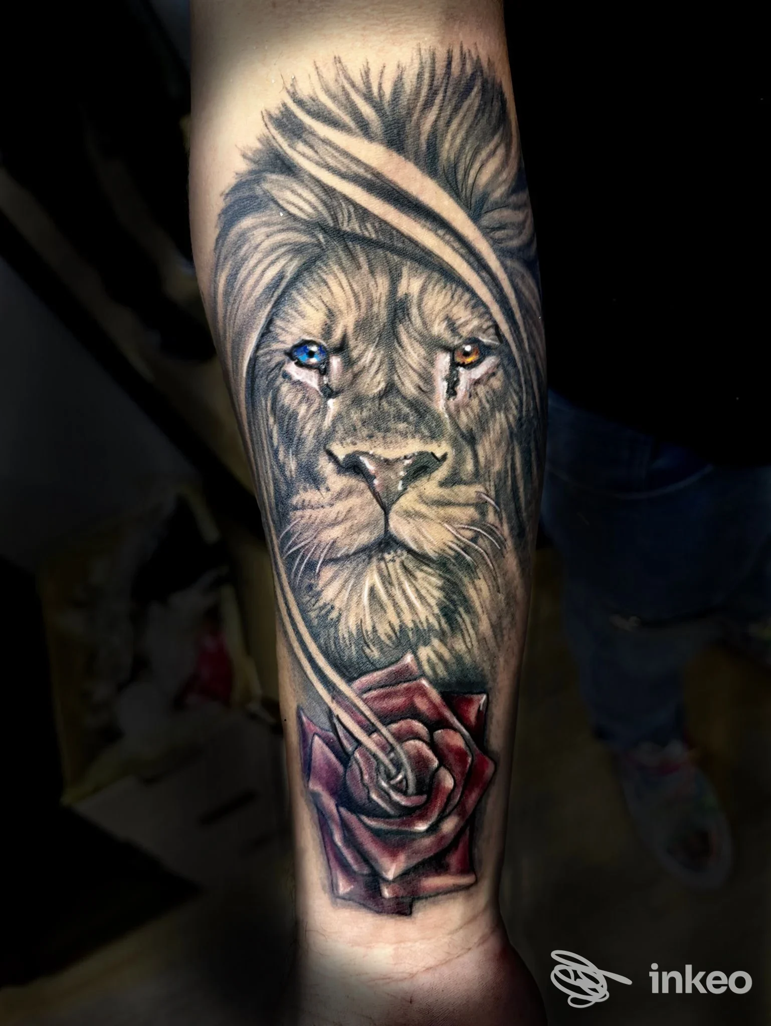 Tatuaggio realistico di leone con occhi colorati e rosa rossa sull'avambraccio, Blink Tattoo Studio, Sorrento.