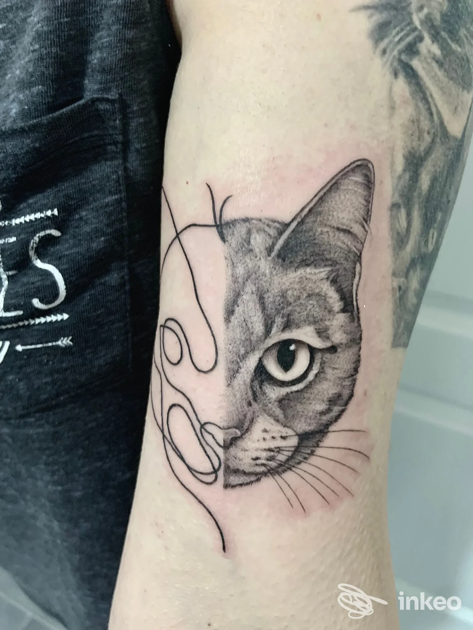 Tatuaggio realistico di un volto di gatto sull'avambraccio, con linee decorative in nero — Opera | Art & Tattoo Crew, Portici.