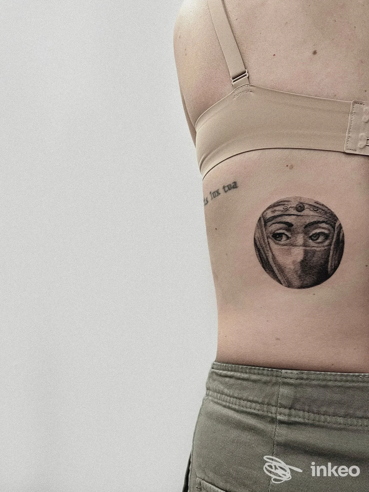 Tatuaggio circolare con occhi velati sul fianco di una persona, ripresa in primo piano. Il Rogo tattoo studio Ferrara.