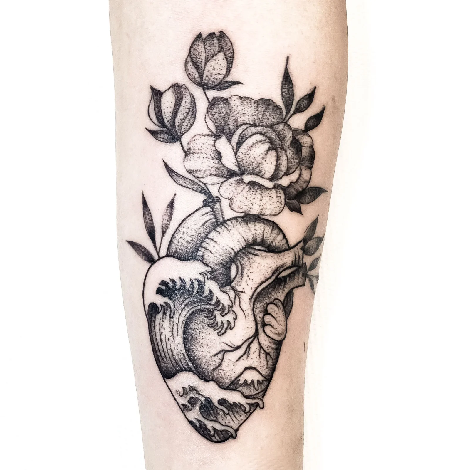 Tatuaggio blackwork a cuore e fiori sull'avambraccio. Skinlab Tattoo Studio, Bologna.