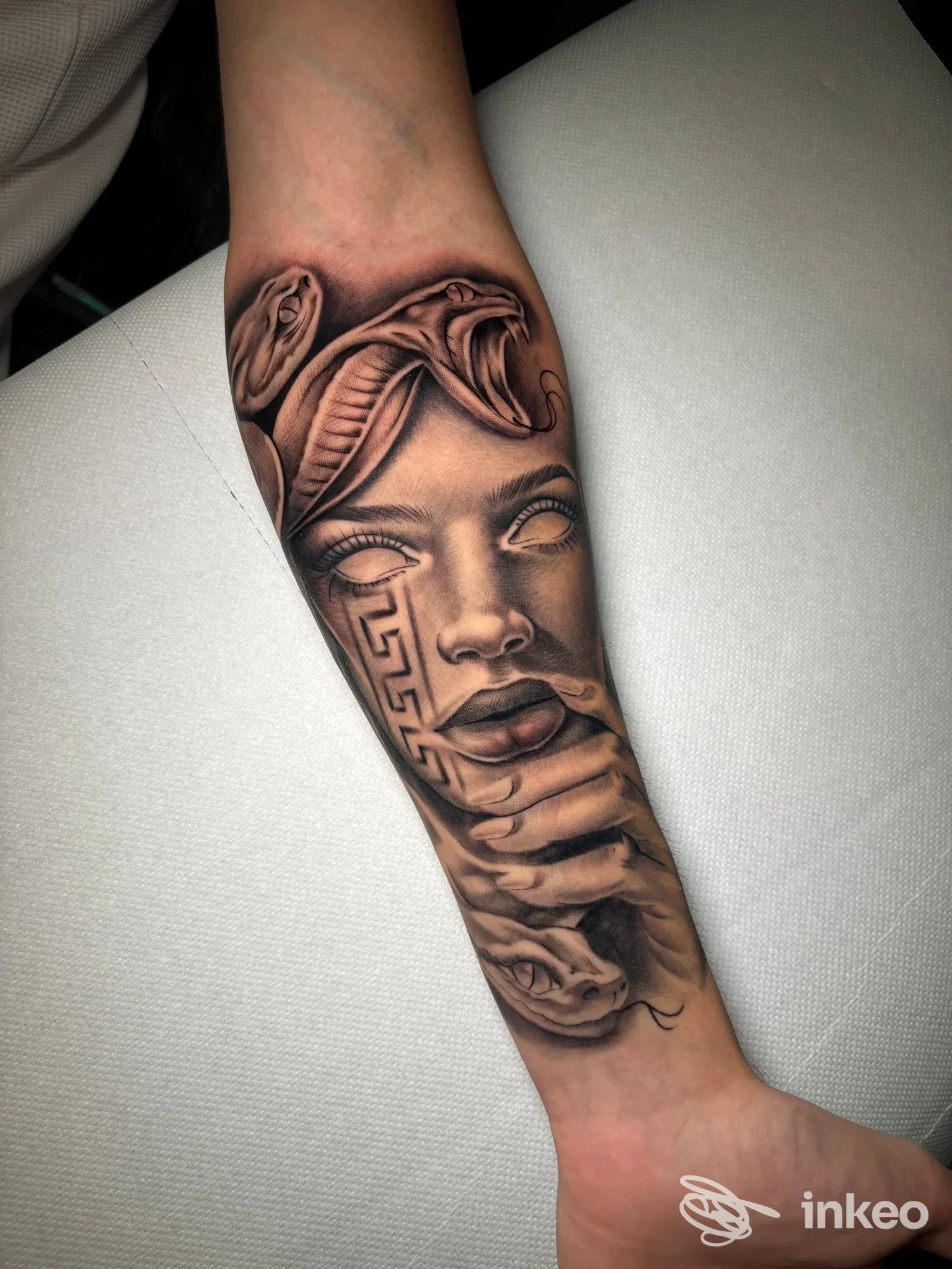 Tatuaggio realistico in bianco/nero su avambraccio fotografato per DelaRoche Tattoo, Lugo: volto stilizzato con dettagli ornamentali.