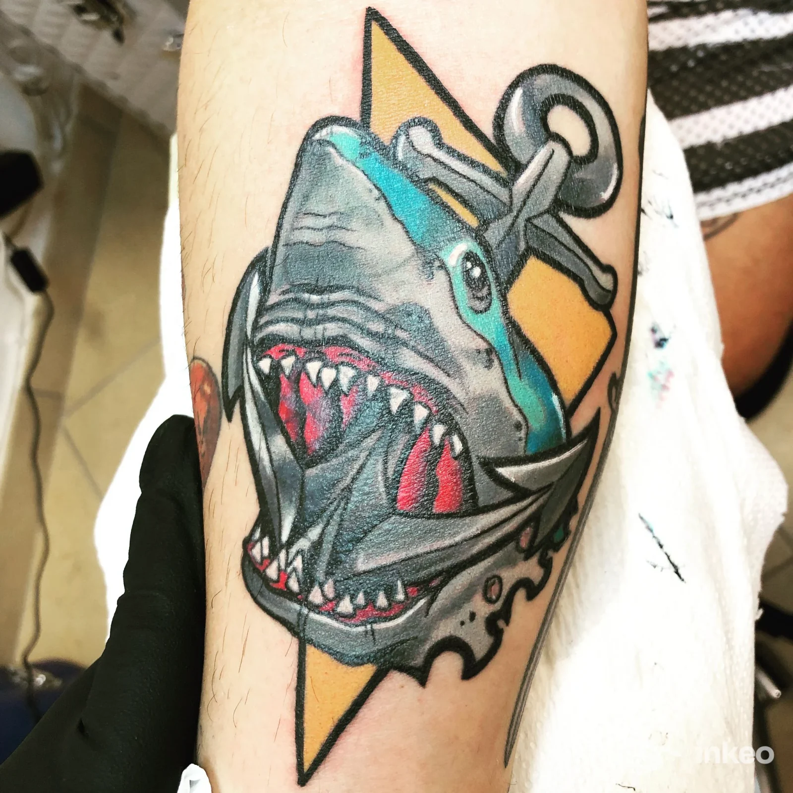 Tatuaggio colorato di uno squalo con ancora sull'avambraccio di un cliente, realizzato presso Notam Nomen Tattoo and Art a Budrio. Vista ravvicinata del lavoro.