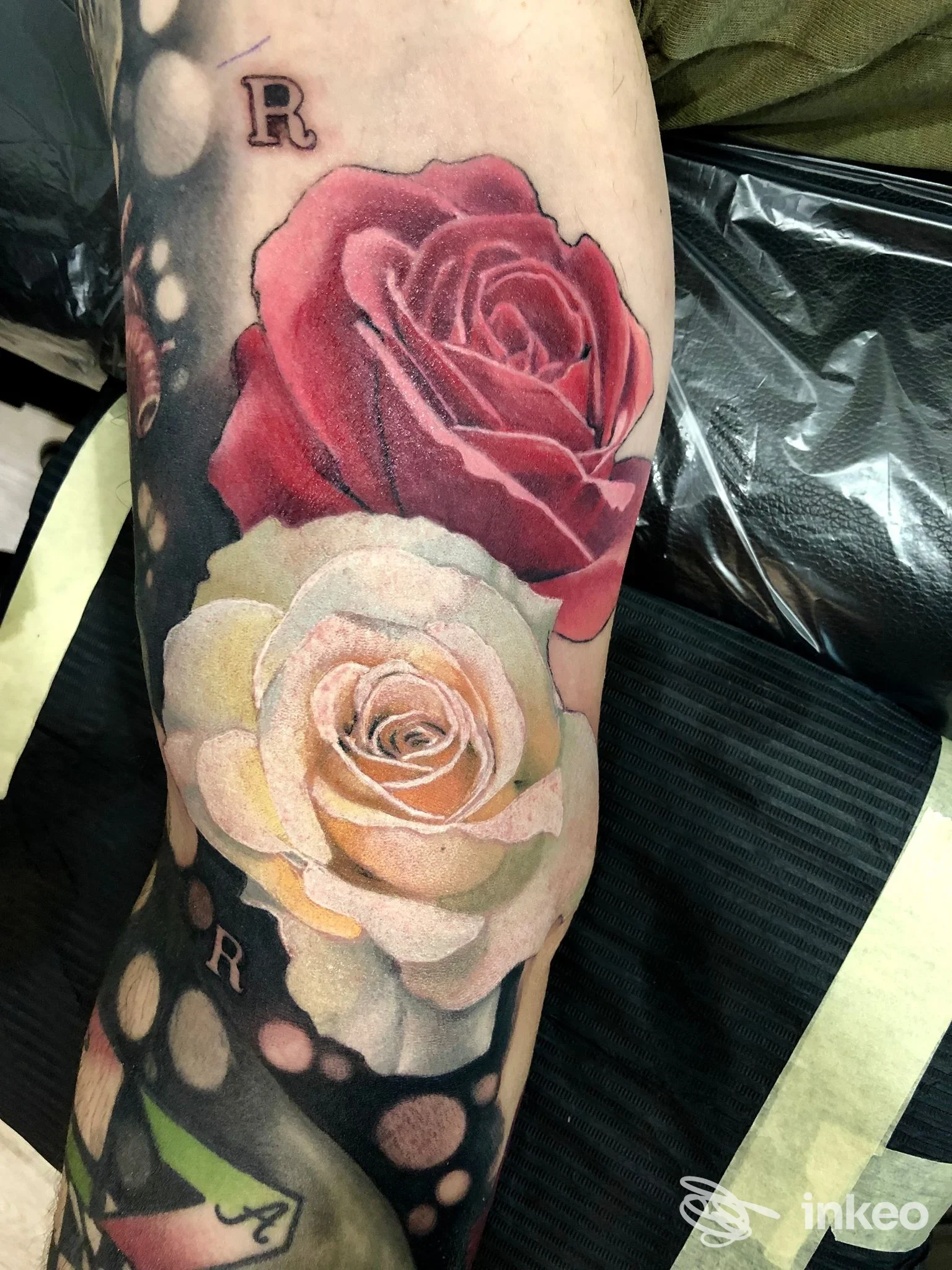 Due rose realistiche tatuate sull'avambraccio con sfondo nero puntinato — foto dallo studio Skullfield Professional Tattoo Lab, Faenza.