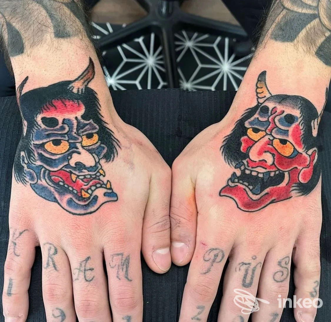 Dorso di entrambe le mani tatuato con due maschere demoniache colorate; foto condivisa da Dice Tattoo Shop, Bologna, mostra il lavoro su pelle reale.