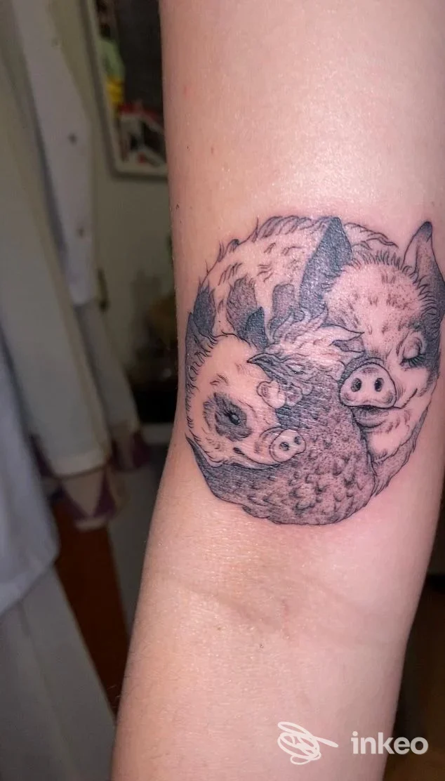 Tatuaggio in bianco e nero sull'avambraccio raffigurante due teste di maiale stilizzate, Ink Rei Tattoo, Faenza.