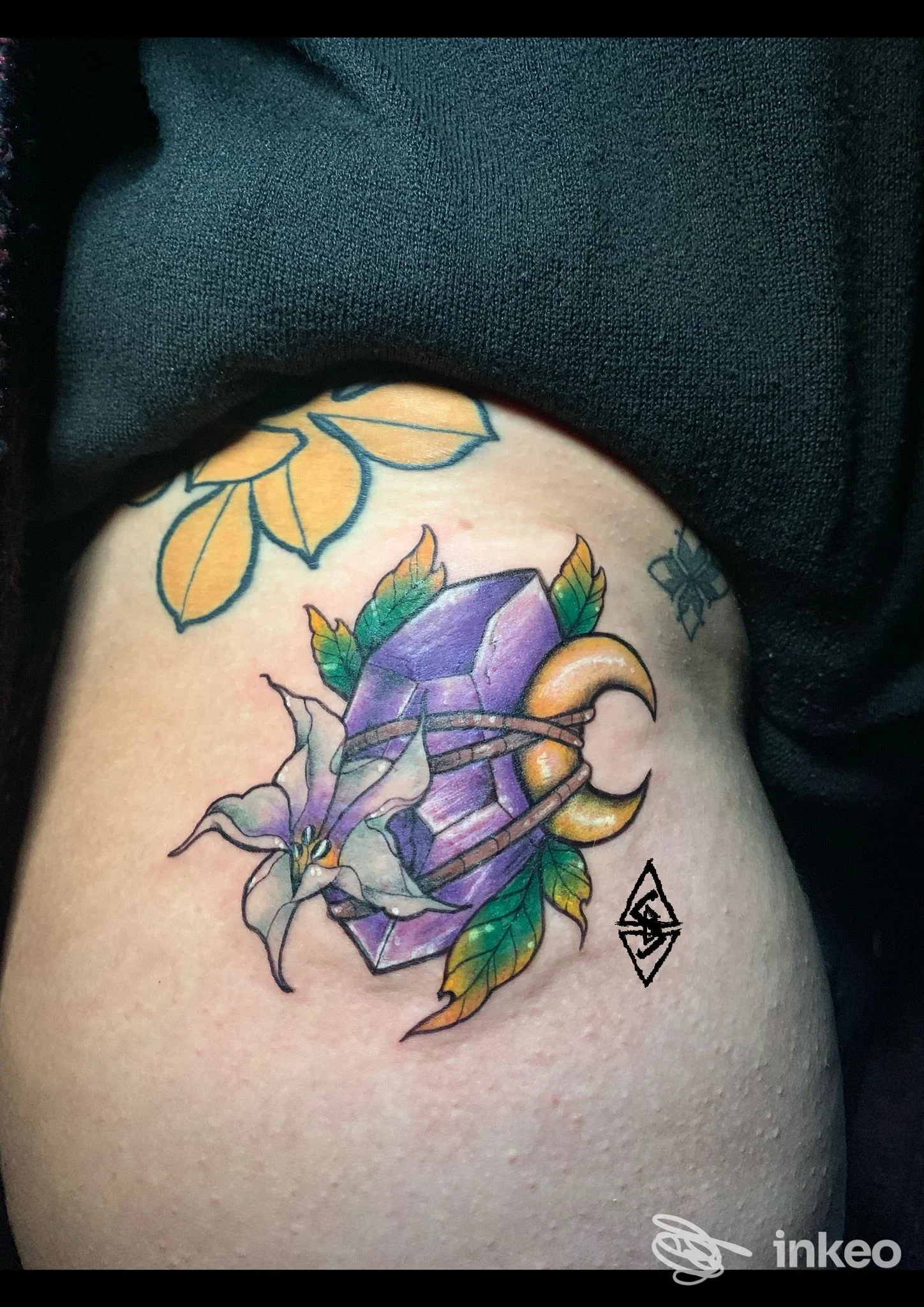 Tatuaggio colorato su coscia/fianco con cristallo viola e fiore, Ars Goetia Tattoo Studio, Ferrara.