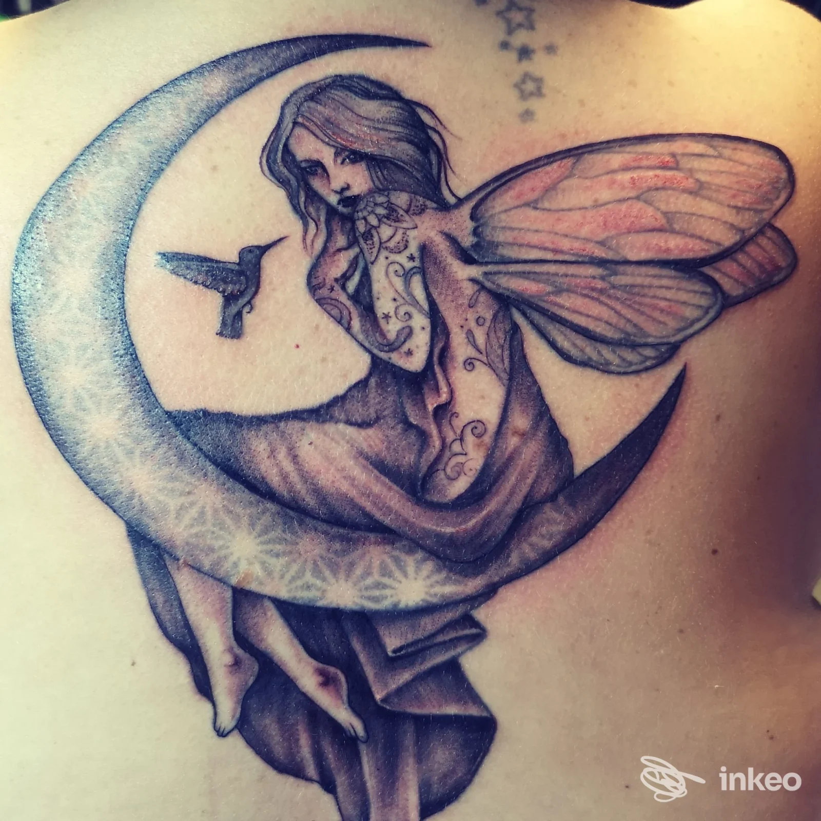Tatuaggio a colori di una fata seduta su una luna a falce sulla parte alta della schiena — No Class Tattoo Shop, Minerbio.
