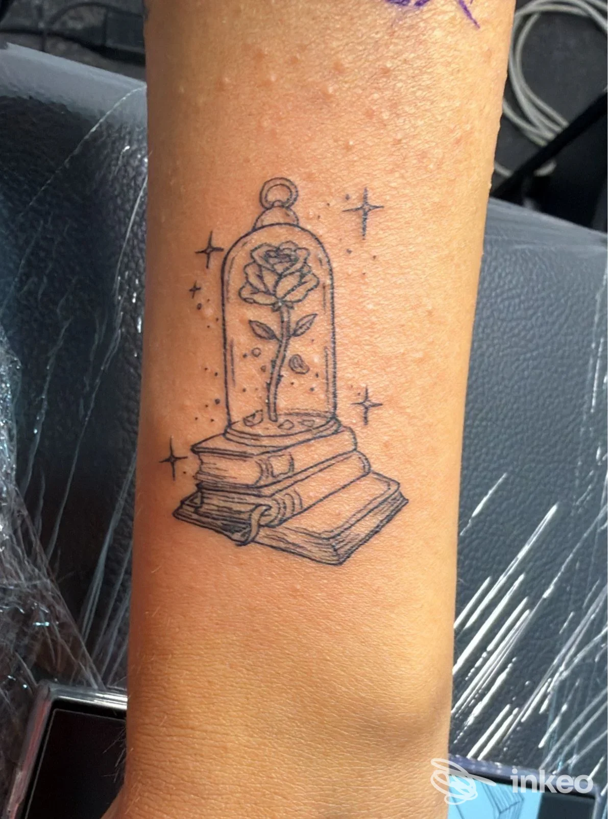 Tatuaggio in nero di una rosa sotto campana su due libri sull'avambraccio, realizzato da Soul Ink Tattoo Studio a Pollena Trocchia.