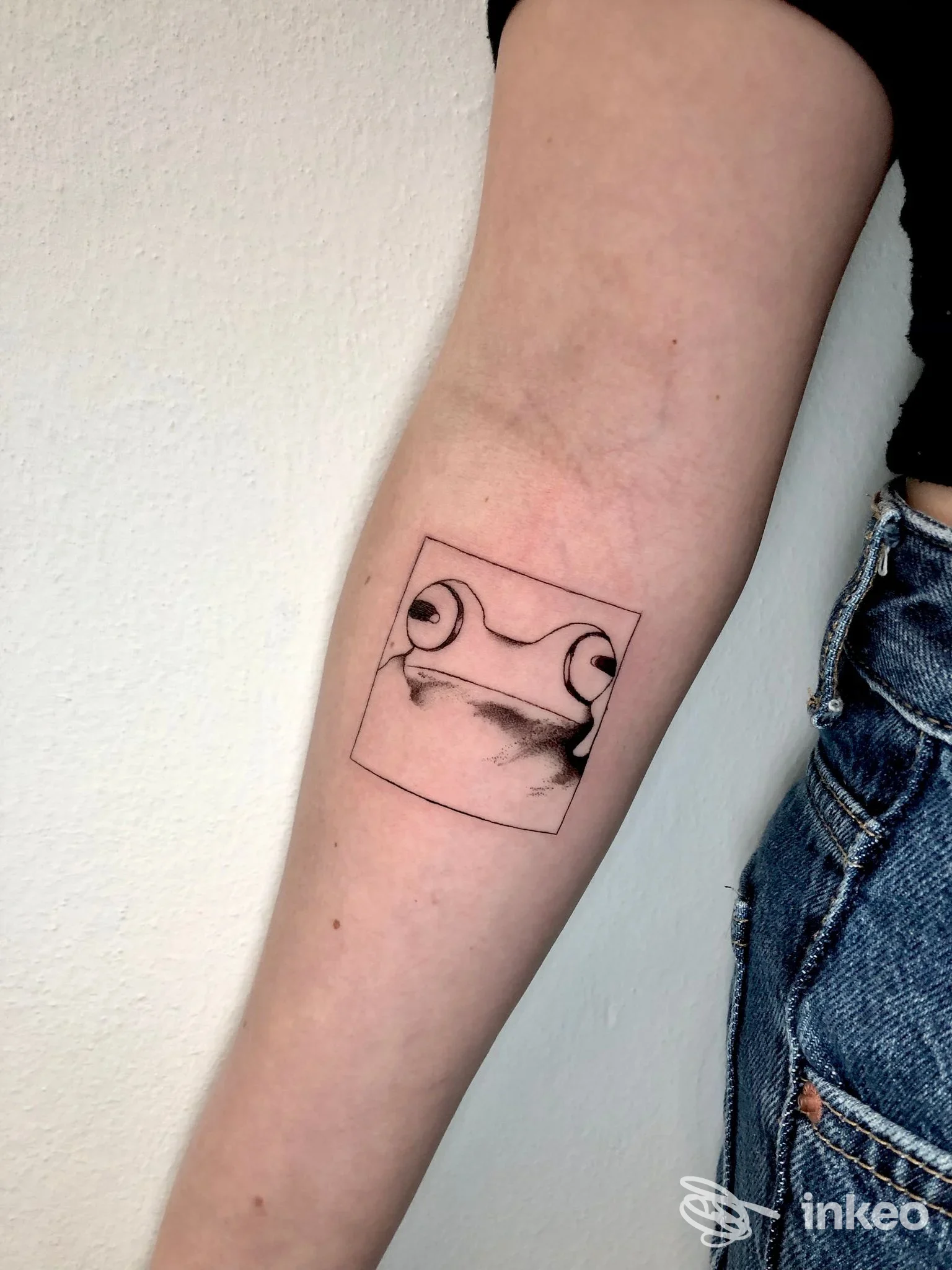 Tatuaggio a inchiostro nero di una rana stilizzata su avambraccio, foto fornita da Indigo Tattoo a Sant'Agata Bolognese.