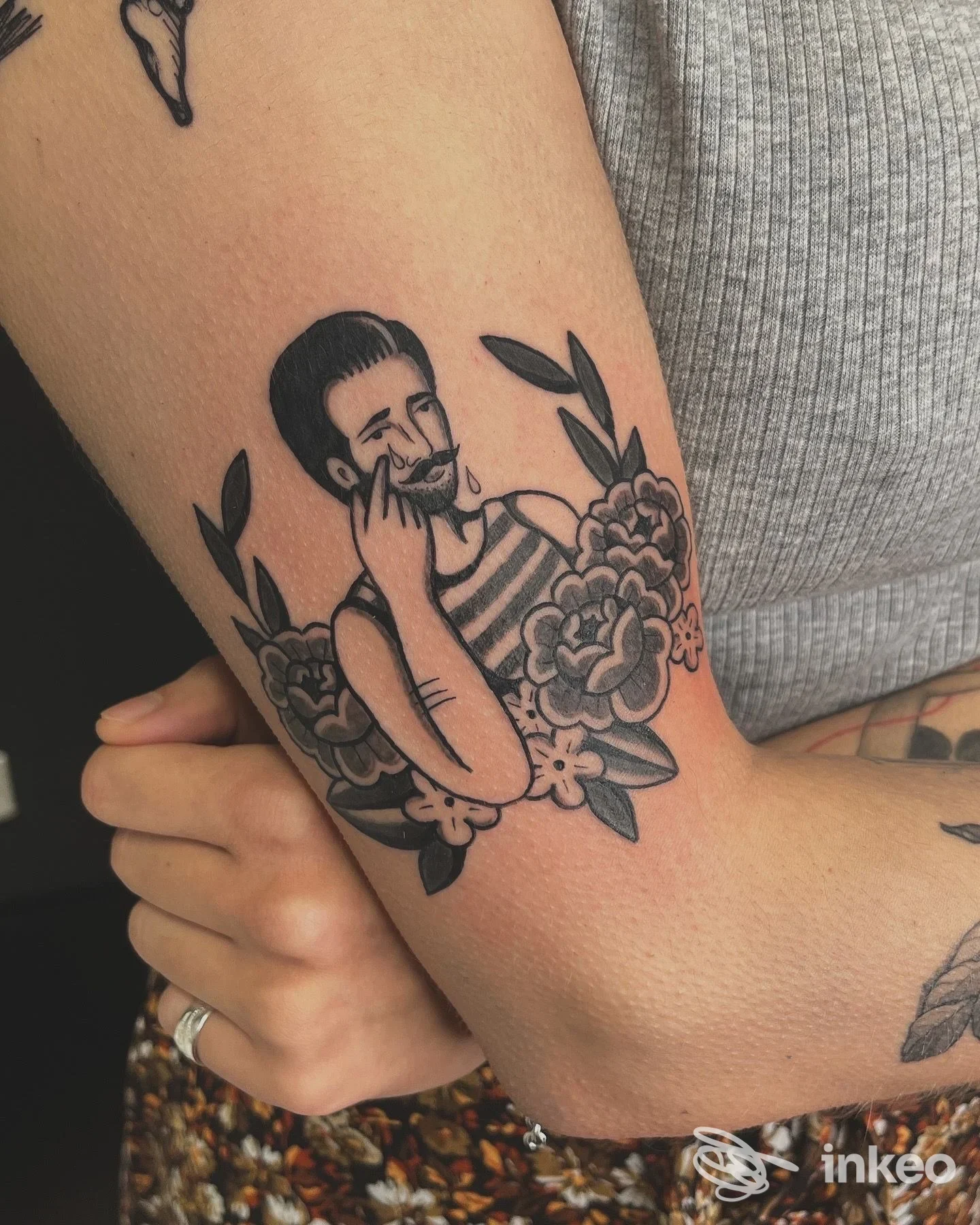 Tatuaggio in bianco e nero su avambraccio raffigurante figura maschile con fiori, realizzato da BOTTEGANERA tattoos and more a Bologna.