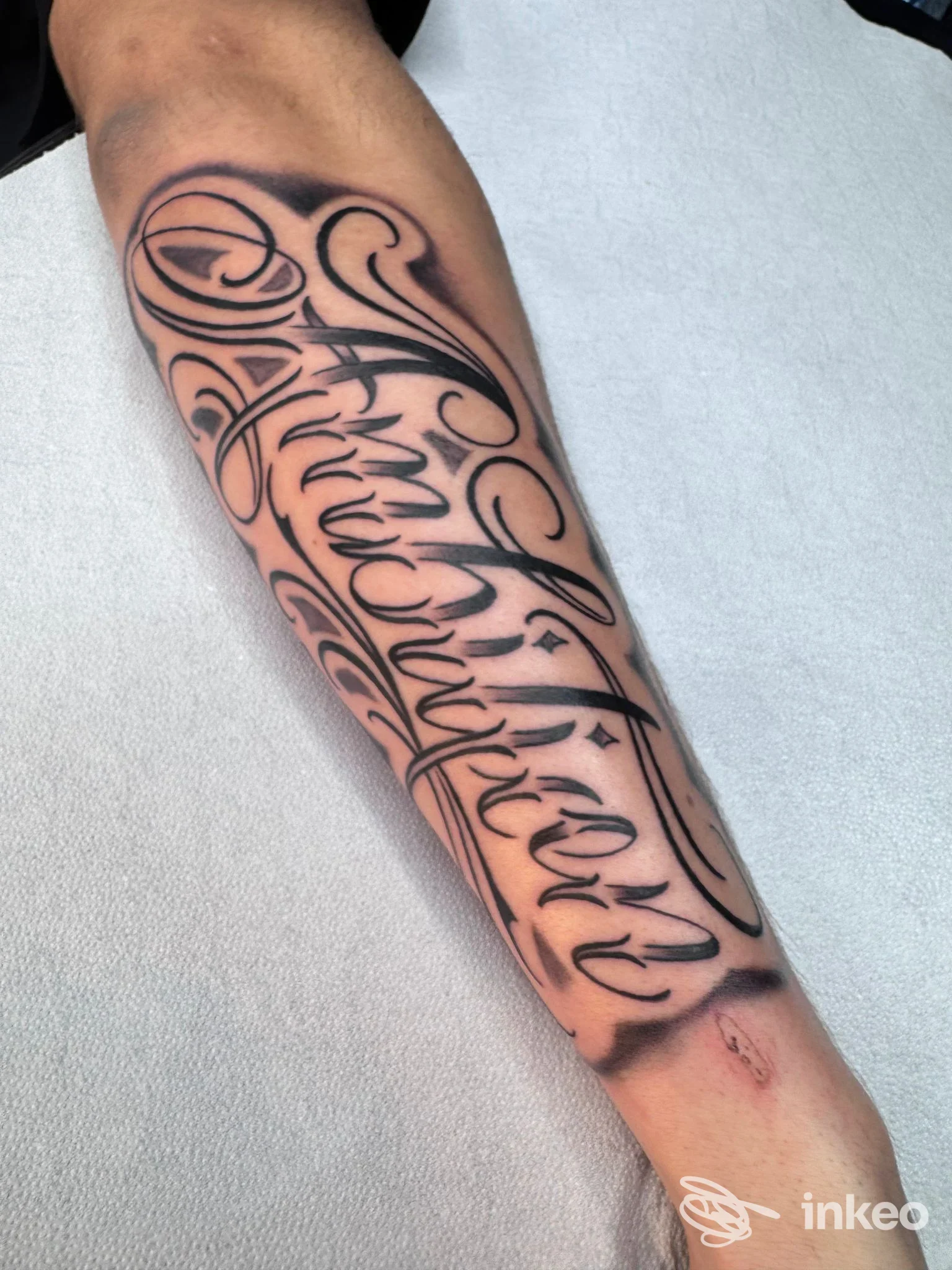 Tatuaggio calligrafico nero su avambraccio, immagine fornita da BIG TATTOO di Simeone Salvatore a Cercola.