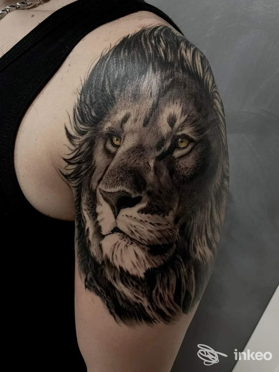 Tattoo realistico a inchiostro nero e grigio raffigurante un leone sul braccio superiore, The Black Tree Tattoo & Piercing, Pomigliano d'Arco.