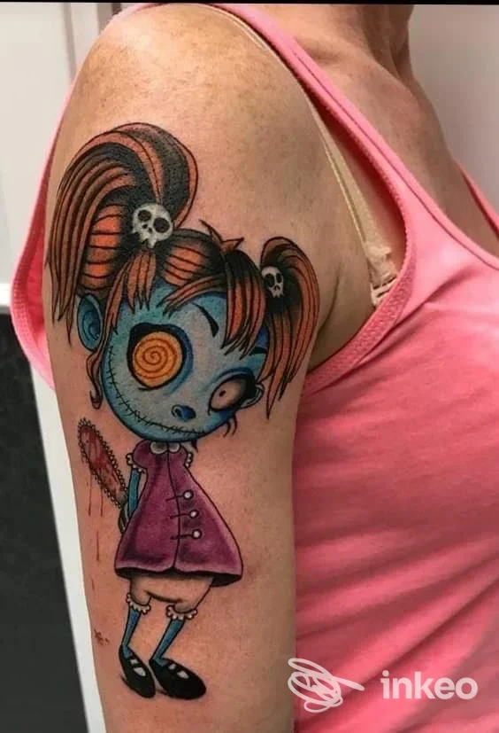 Tatuaggio colorato su braccio superiore: bambina in stile cartoon blu e arancio, immagine inviata da Riff Raff Tattoo / Tricopigmentazione, Nola.