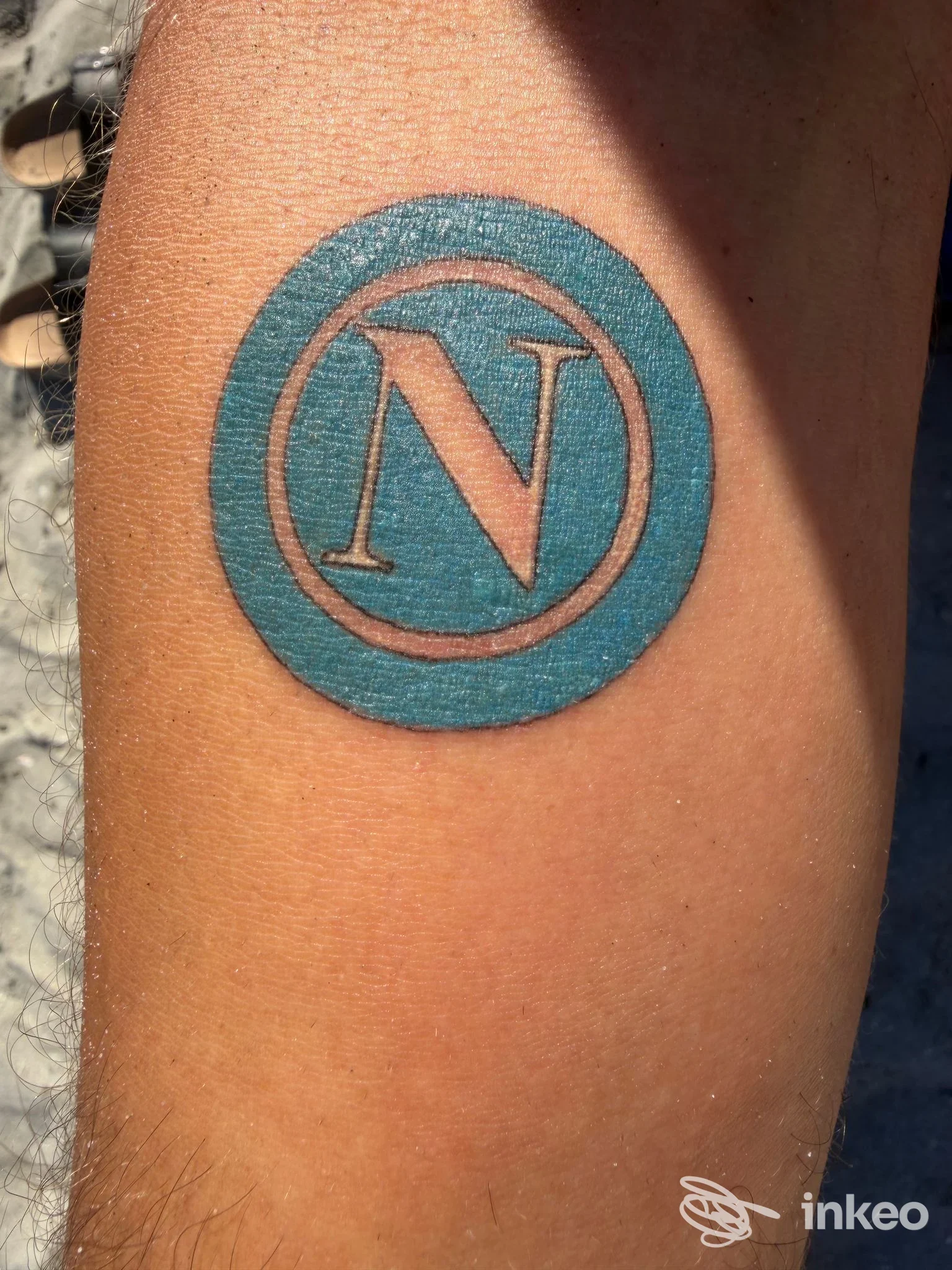 Tatuaggio circolare con lettera 'N' sull'avambraccio, foto inviata da Indelebile Tattoo Studio a Ravenna.