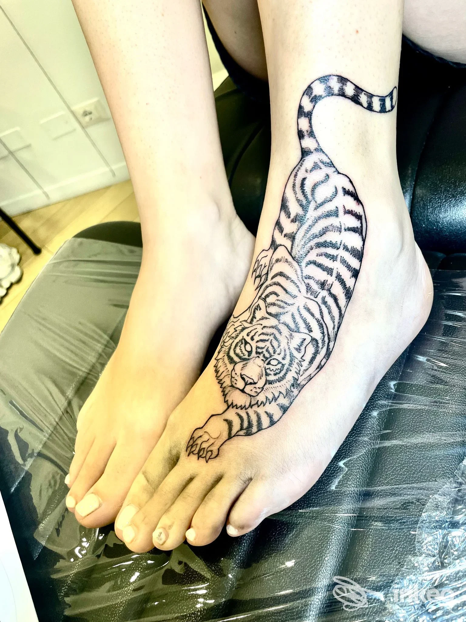 Tatuaggio di una tigre in nero sul dorso del piede e caviglia, foto condivisa da Eva Tattoo, Bologna.