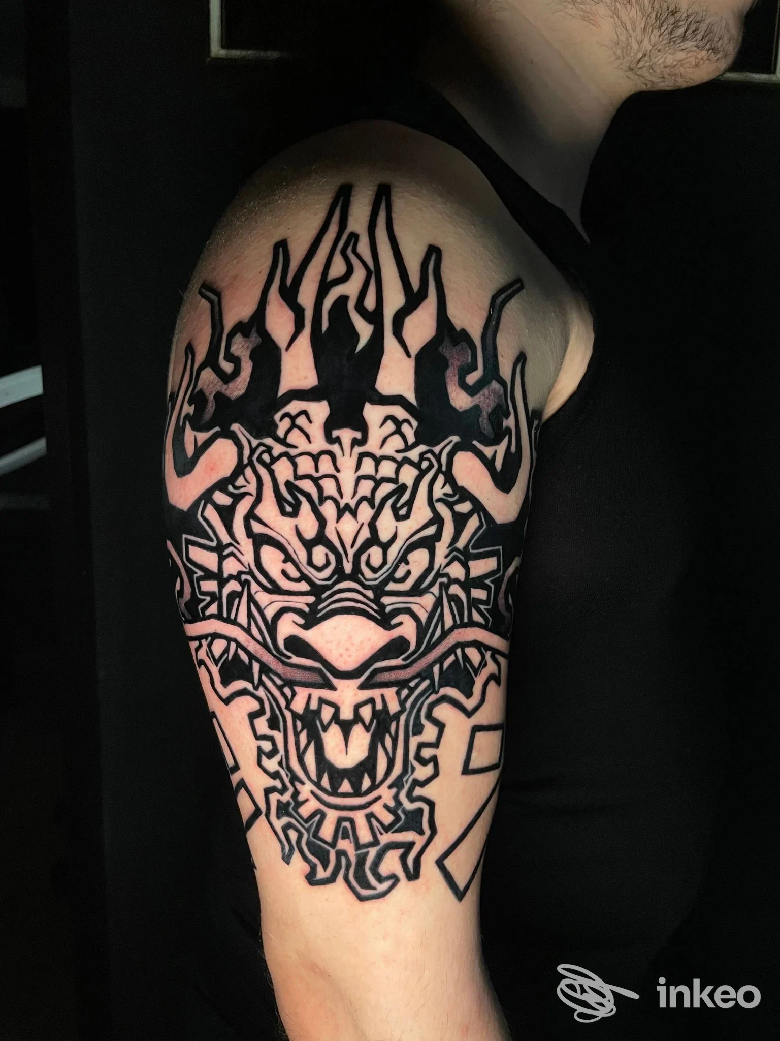 Tatuaggio nero su braccio superiore raffigurante una testa stilizzata, foto d'insieme scattata nello studio Ink Klub Tattoo Shop, Ravenna.