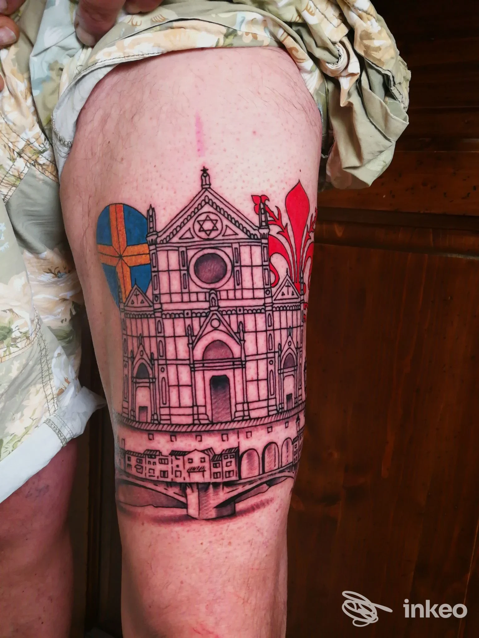 Tatuaggio su coscia con facciata architettonica e dettagli rossi e blu, Calavera TattooParlor, Prato.