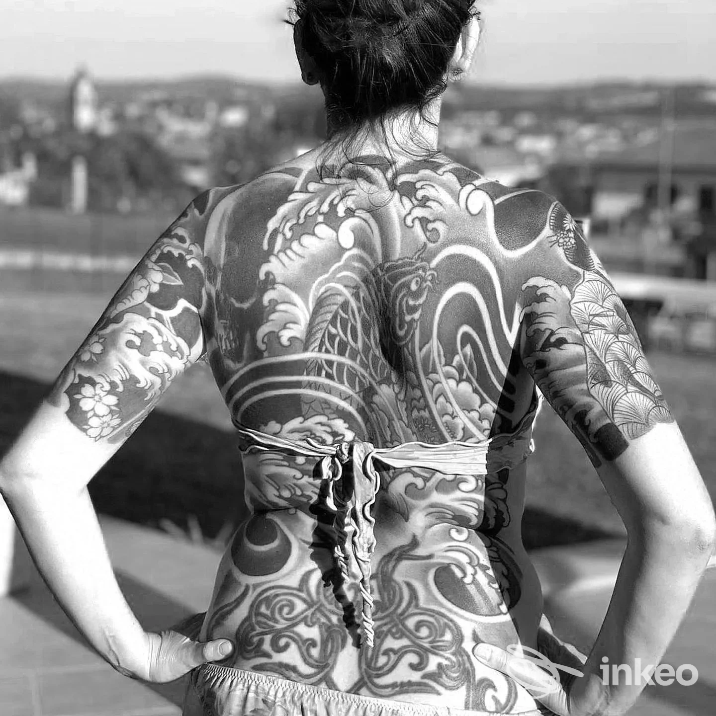 Donna di schiena con tatuaggio esteso su schiena e braccia, fotografia di EVOL tattoo studio, Alessandria.