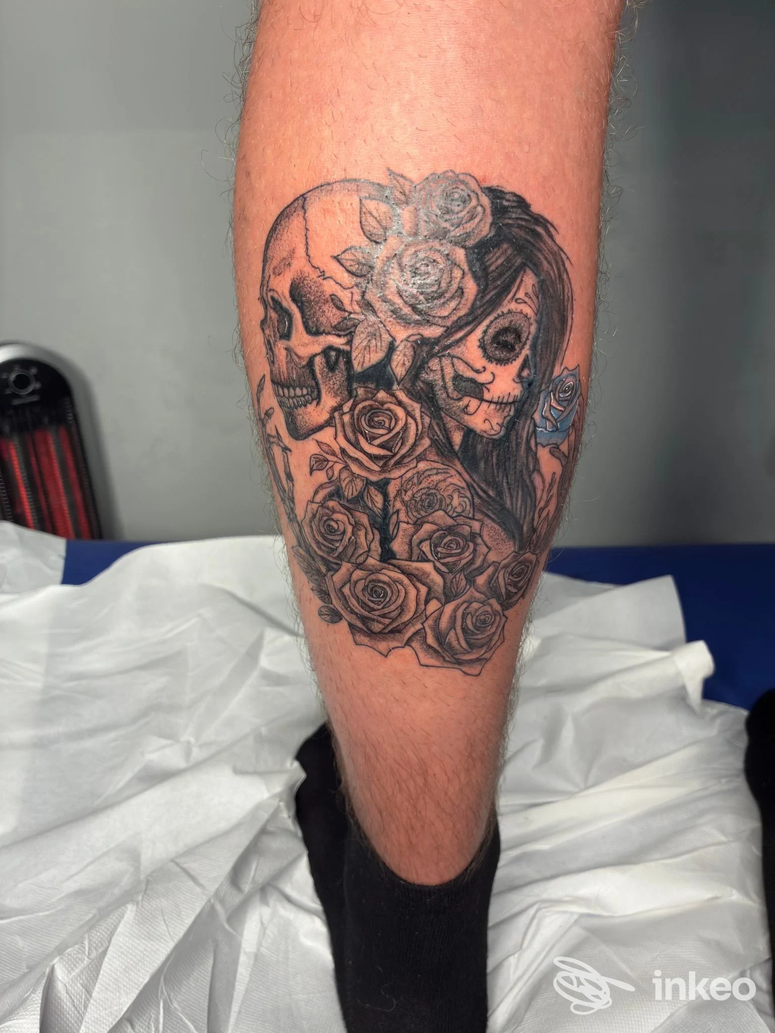 Tatuaggio in bianco e nero raffigurante teschio, volto femminile stilizzato e rose sul polpaccio — More Art Tattoo, Stroppiana.
