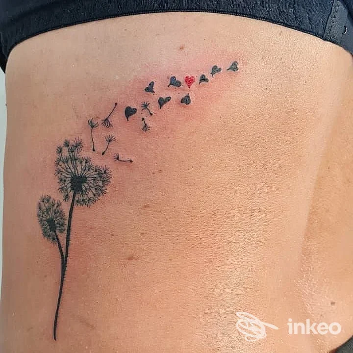 Tatuaggio sul fianco di un soffione con semi che si trasformano in cuori, eseguito da Sottopelle Tattoo Studio a Mirano.