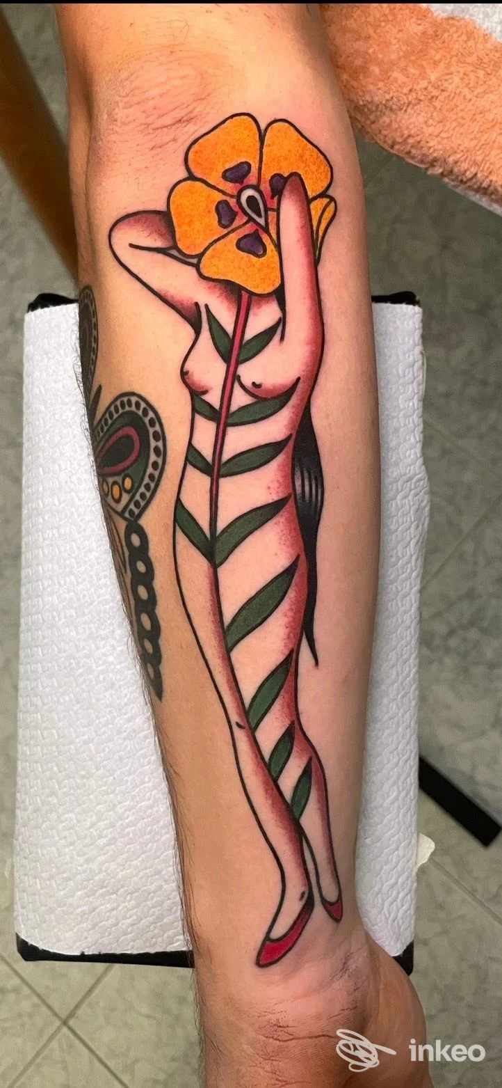 Tatuaggio su avambraccio con figura femminile stilizzata che regge un grande fiore giallo – Blue Bird Tattoo Studio, Firenze.
