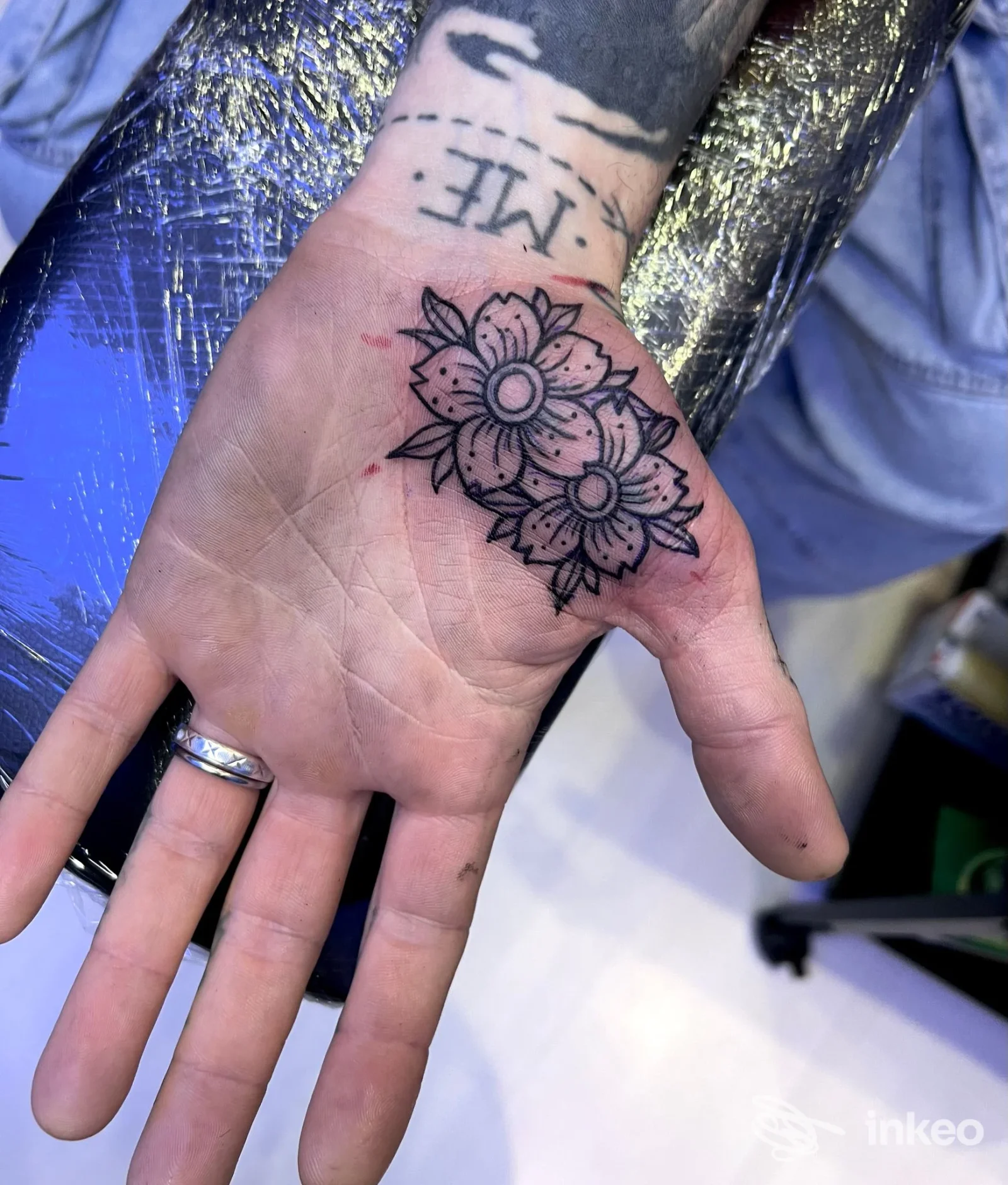 Mano con tatuaggio di due fiori stilizzati sul palmo, scatto in CN Tattoo Studio a Porto Viro.